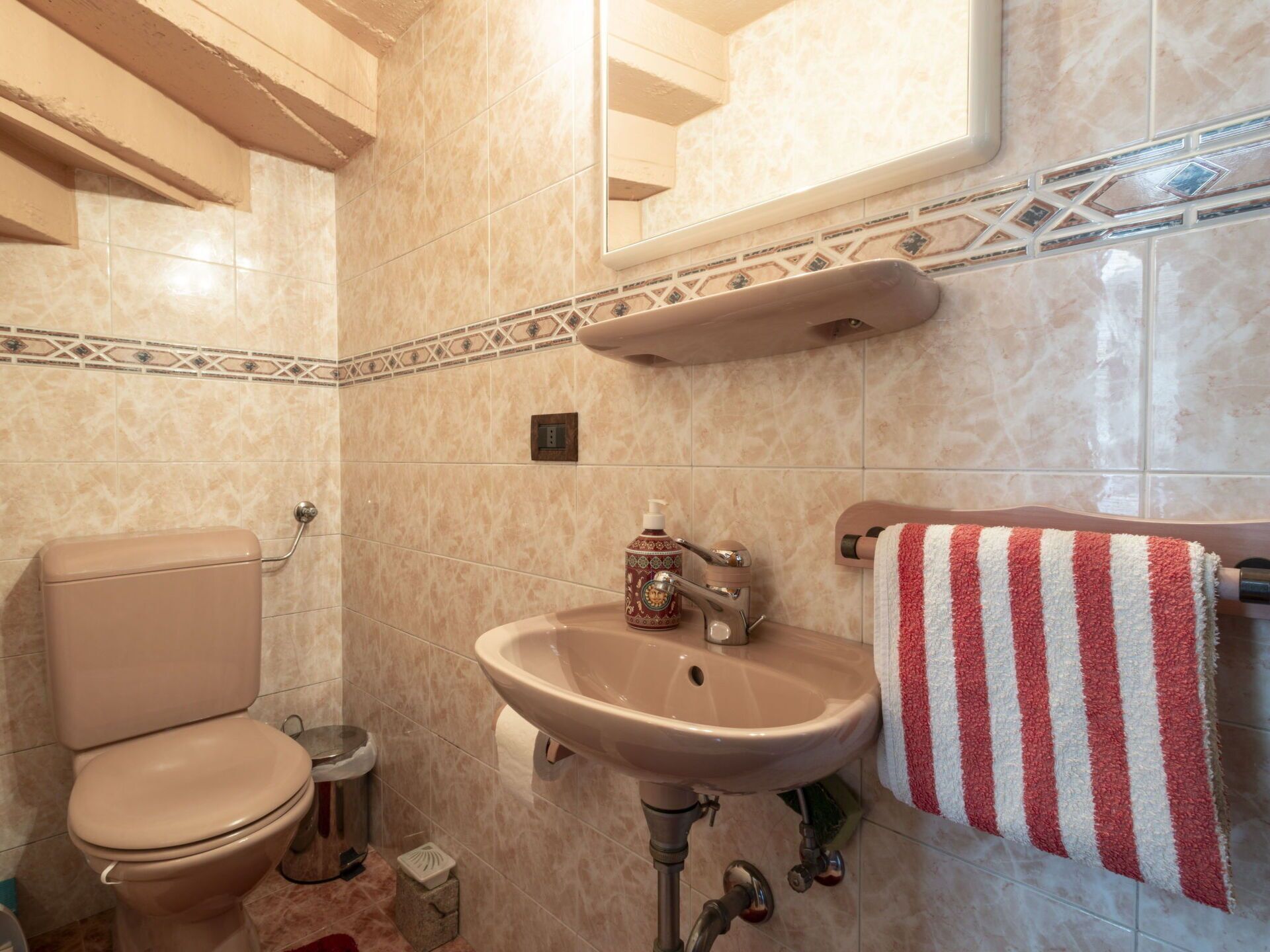 Un baño con inodoro, lavamanos y perchero para toallas.