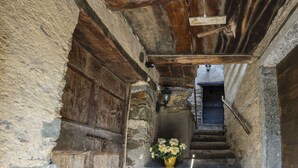 Una estrecha escalera de piedra con una puerta de madera y un jarrón de flores al final.