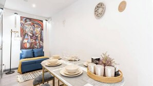 A dining area with a round table set for four, a blue sofa, and a large abstract painting on the wall.
