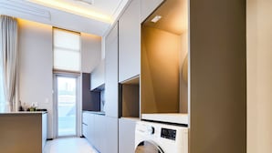 A modern kitchen with built-in appliances, a washing machine, and a large window. - Parami On (Busan)