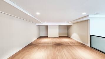 A spacious room with wooden flooring and white walls, featuring recessed ceiling lights and a visible closet.