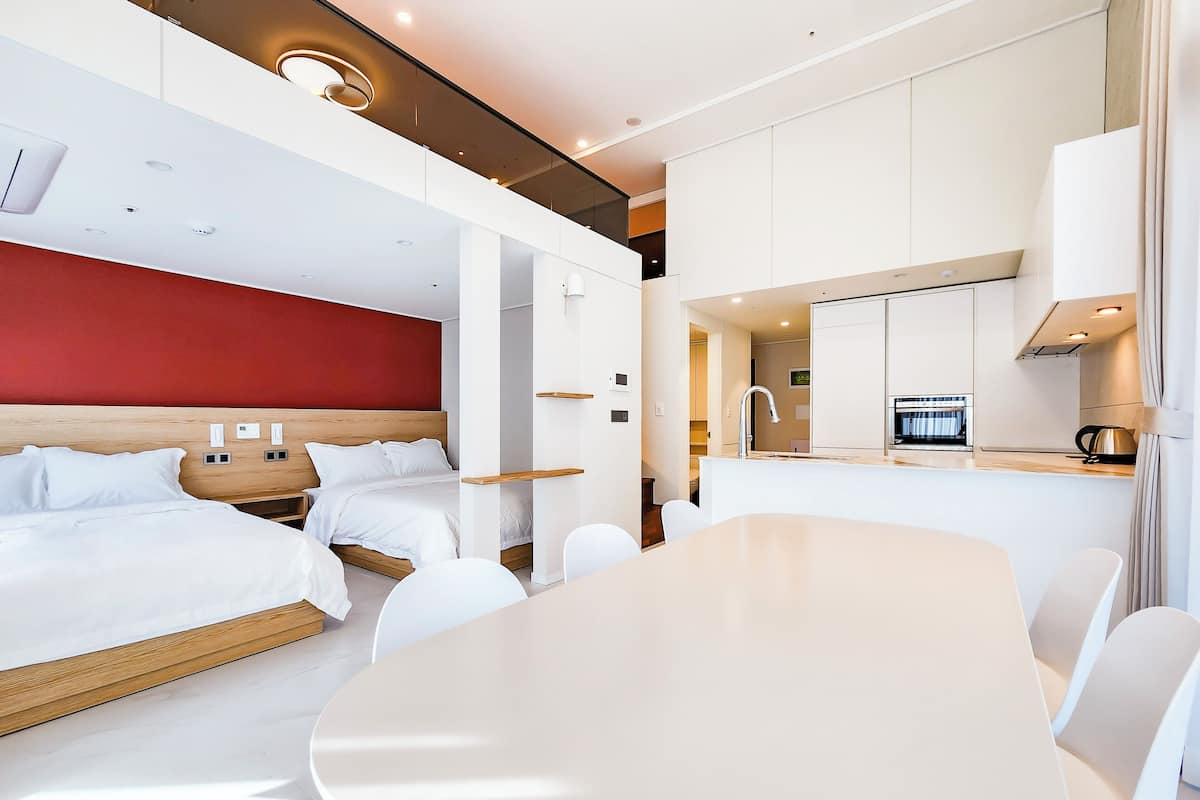 Una habitación de hotel moderna con una cama grande, una mesa de comedor y una kitchenette.