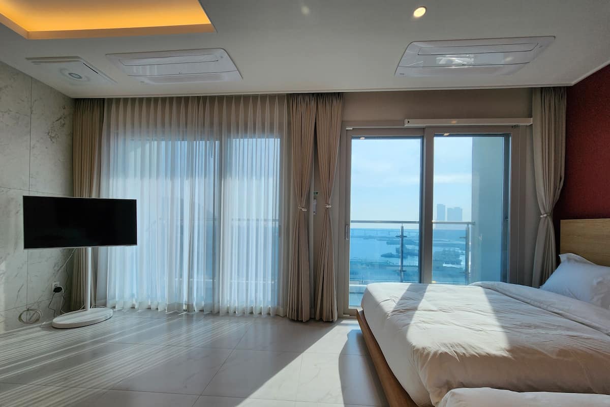 Habitación de hotel con una cama grande, televisión y vistas a la ciudad.