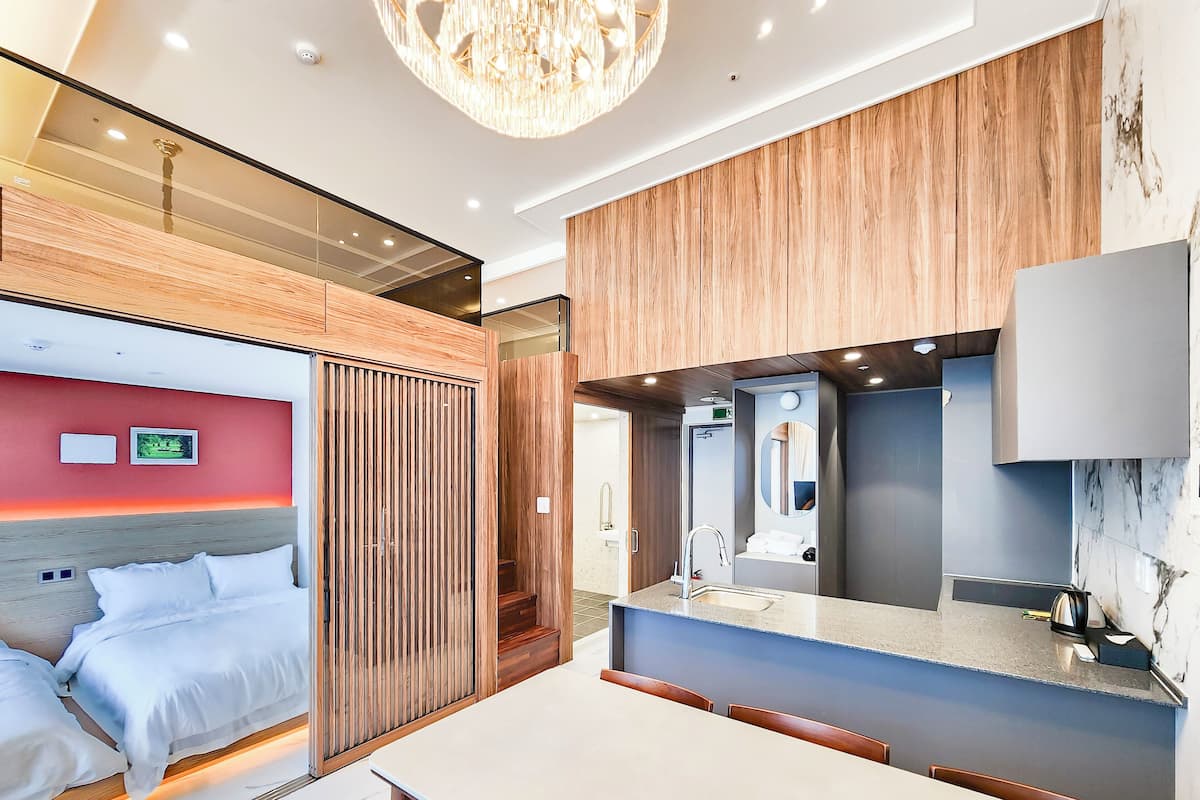 Una habitación de hotel moderna con cama, escritorio y baño con espejo y lavamanos.