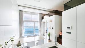 A modern kitchen with a large window, a marble countertop, and a built-in sink. - Parami On (Busan)