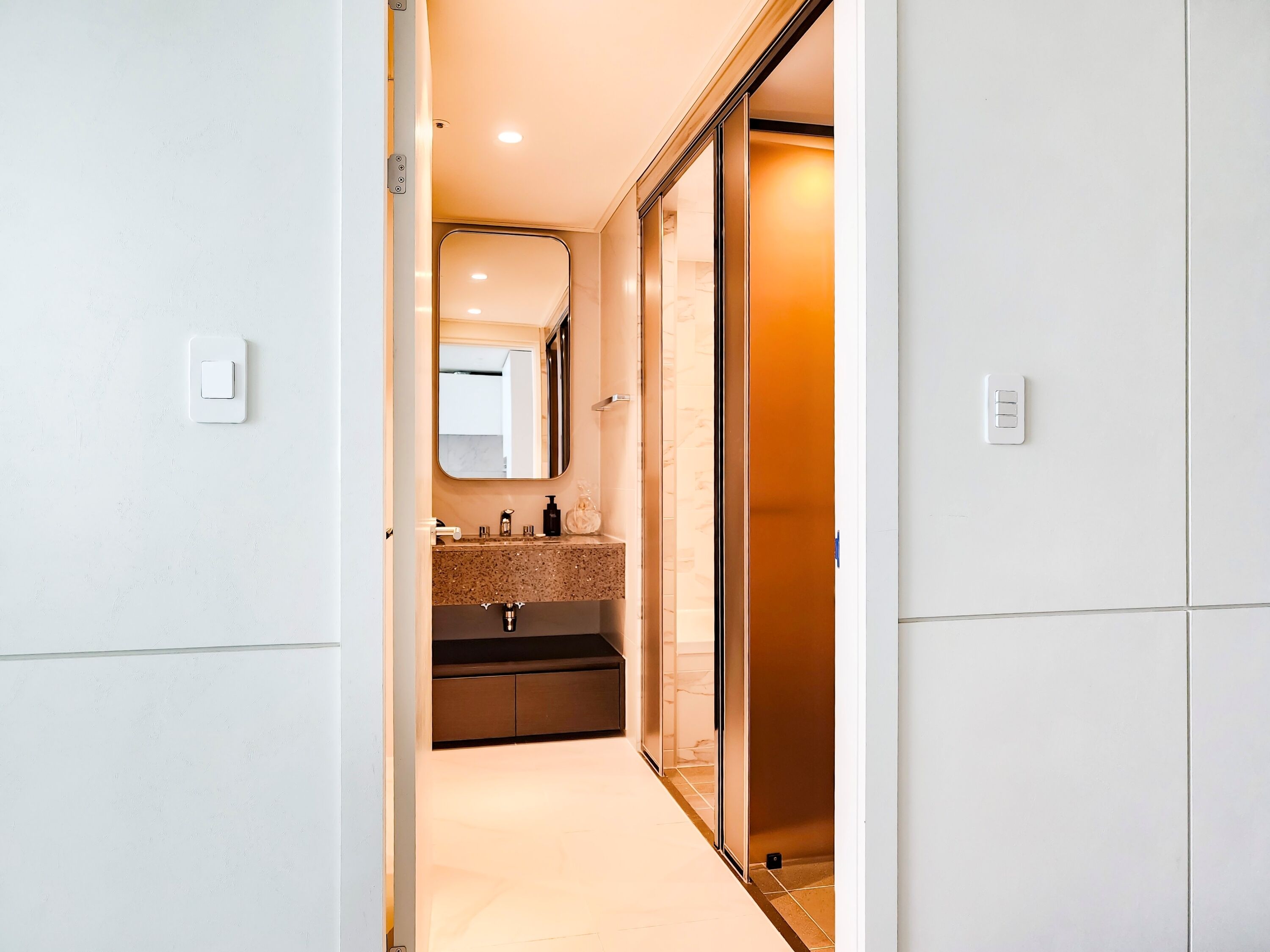 A modern bathroom with a vanity, mirror, and a shower area.