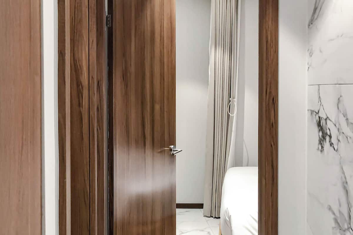 Un dormitorio con una cama, una puerta de madera y un suelo de mármol.