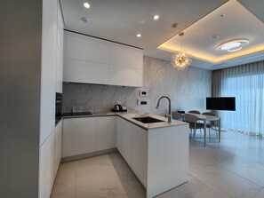A modern kitchen with a built-in island, a flat-screen TV, and a chandelier. - Parami On (Busan)