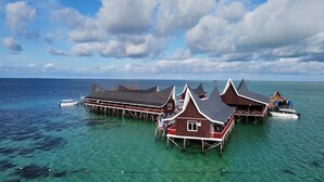 Overwater bungalows with multiple decks, clear turquoise water, and a boat docked nearby. - Semporna Water House (Semporna)