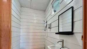 A small, narrow bathroom with white wooden walls, a white sink, and a mirror. - Semporna Water House (Semporna)