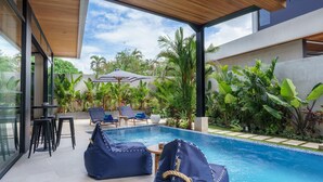 Un espace piscine extérieur moderne, agrémenté de coins salon et d’une végétation luxuriante.