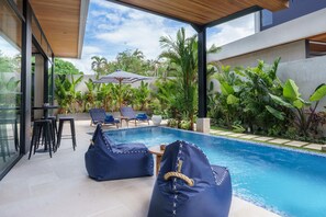 A modern outdoor pool area with seating and lush greenery.