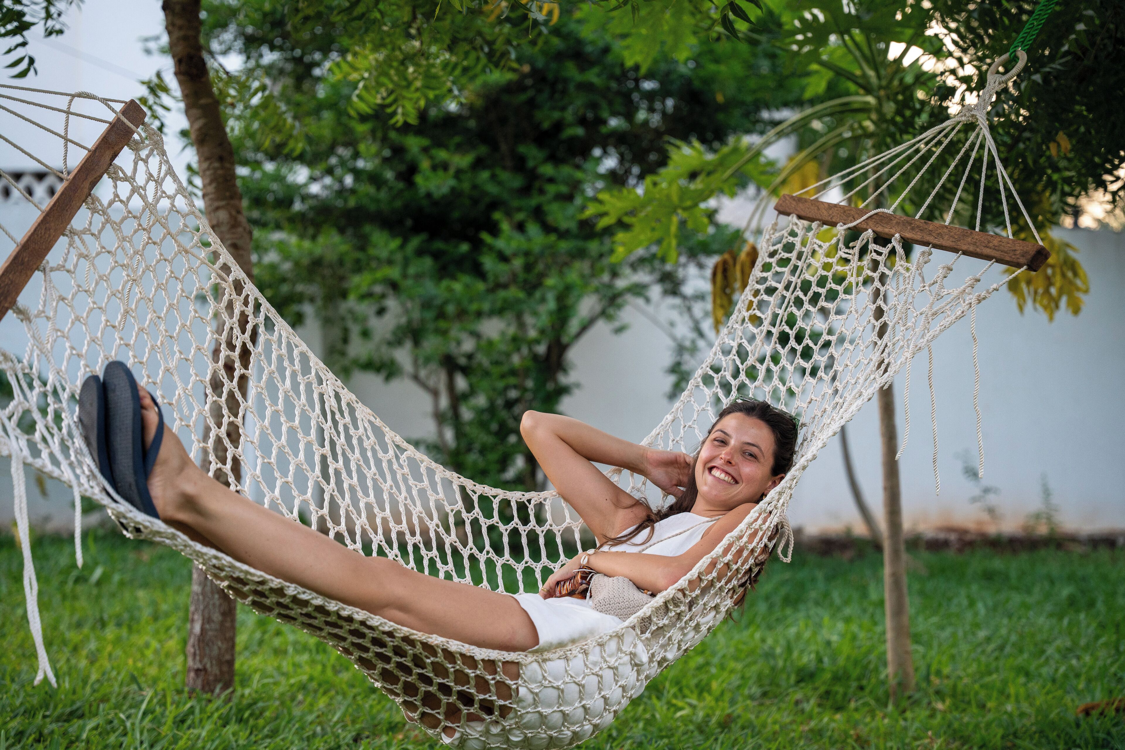 A hammock suspended between trees in a grassy area.
