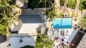 An aerial view of a resort with a swimming pool, palm trees, and lounge chairs. - Hostel 197 (Nungwi)