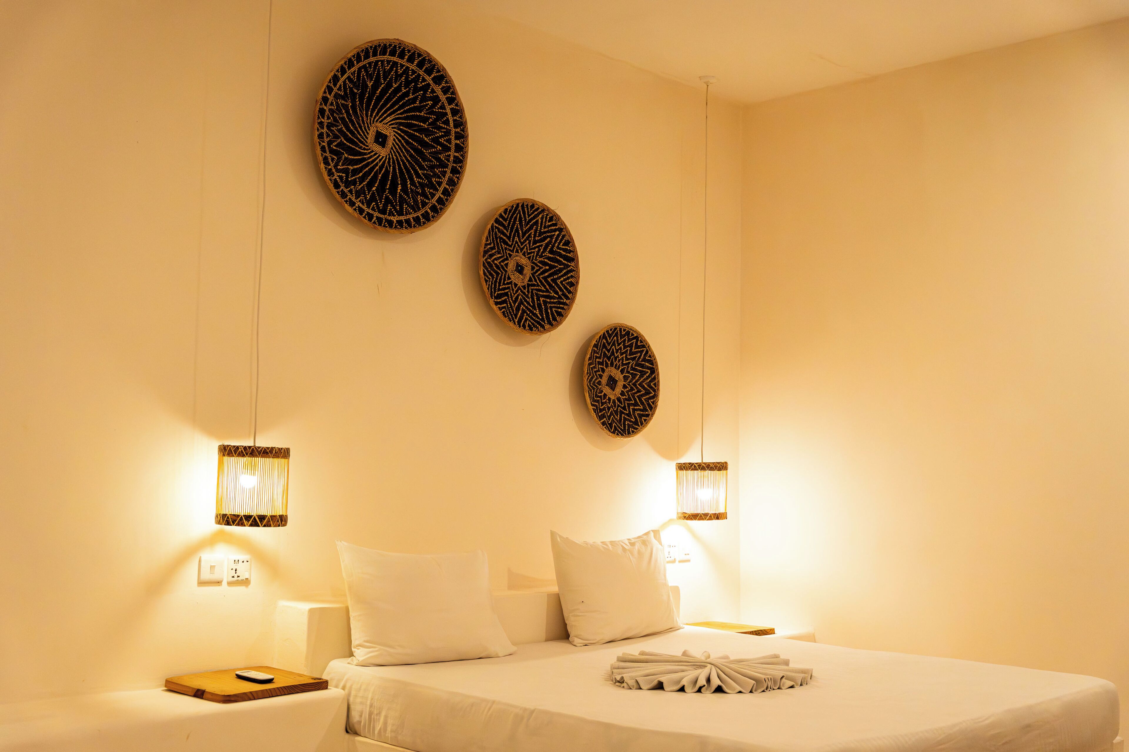 A hotel room with a neatly made bed, a bedside table with a remote control, and decorative wall art.