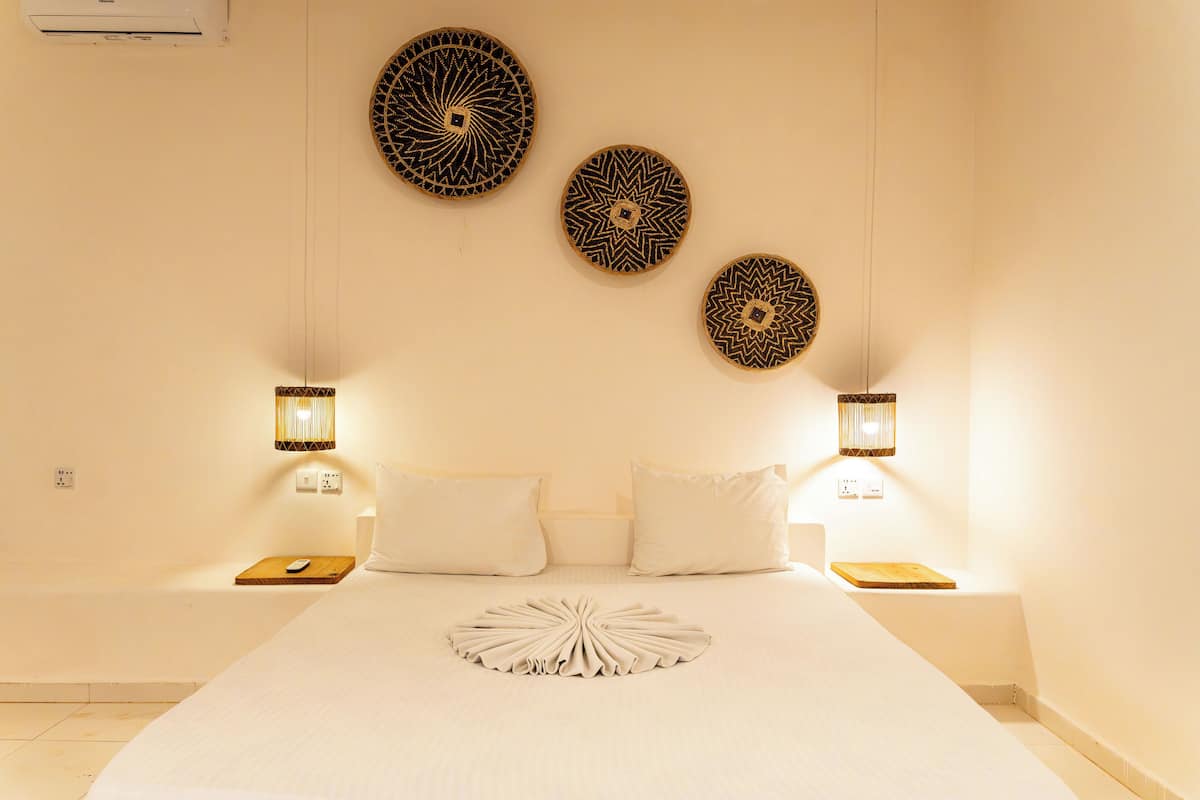 Habitación de hotel con una cama grande, dos mesitas de noche y tres adornos de pared.