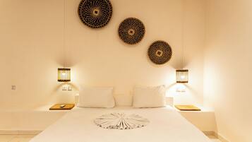 Habitación de hotel con una cama grande, dos mesitas de noche y tres adornos de pared.