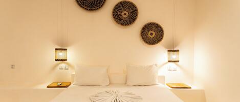 Habitación de hotel con una cama grande, dos mesitas de noche y tres adornos de pared.