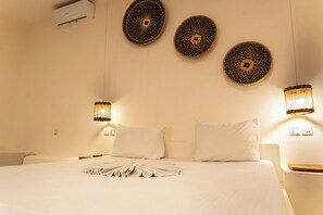 A hotel room with a large bed, two bedside tables, and three wall-mounted decorative plates. - Hostel 197 (Nungwi)
