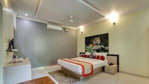 A bedroom with a bed, bedside tables, a desk, and a painting on the wall. - Tiger King Resort (Chimur)