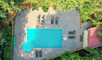 Vista aérea de un área de piscina con una pileta rectangular, rodeada por un deck pavimentado y delimitada por un muro bajo.