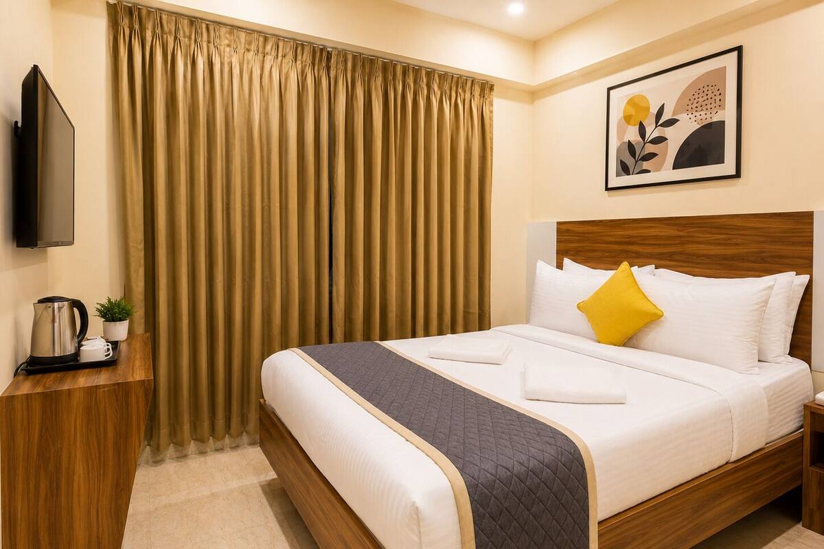 A hotel room with a bed, a television, a coffee maker, and a painting on the wall.