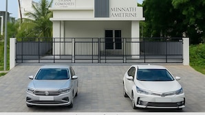 Un edificio a più piani con balconi, con la scritta "MINNATH AMETRINE" e "URBAN COMFORTS". Due auto sono parcheggiate davanti.