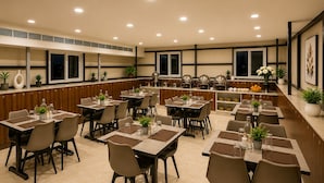 Un ristorante con diversi tavoli e sedie, un'area bar con una griglia e piante in vaso.