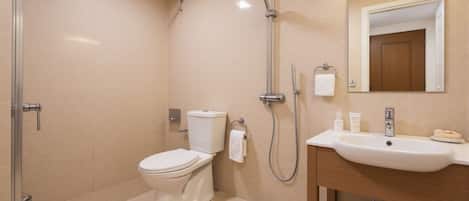 Un baño moderno con inodoro, ducha, lavamanos y espejo.