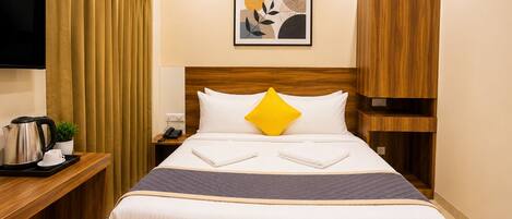 Een hotelkamer met een bed, nachtkastje en een aan de muur bevestigde televisie.