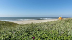 A beach with a lifeguard tower, grassy dunes, and the ocean. - Seaside Holiday Home with Garden (Groote Keeten)