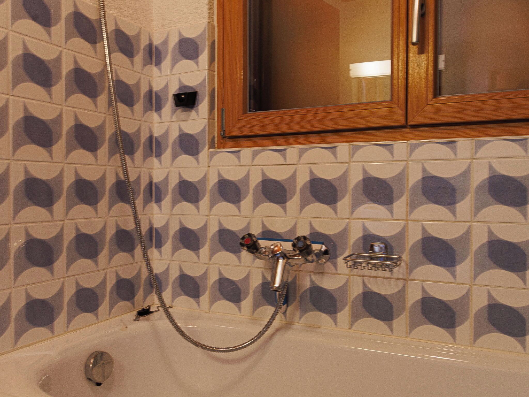 A bathroom with a bathtub, a shower, and a wooden cabinet above the mirror.