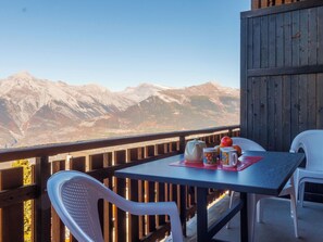 A balcony with a table and chairs, a wooden railing, and a view of mountains. - Hortensia 33 by Interhome (Veysonnaz)