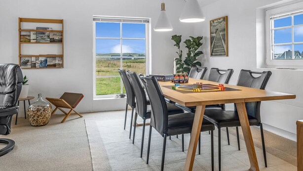 Un comedor moderno con una mesa de madera, sillas negras y vistas al exterior a través de amplios ventanales.