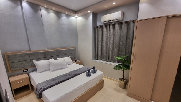 A modern bedroom with a large bed, bedside tables, a wardrobe, and a potted plant. - Cairo Plaza Manchester Hotel (Cairo)
