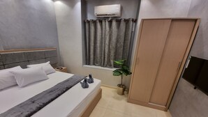 A hotel room with a bed, a bedside table, an air conditioning unit, a window with curtains, a potted plant, and a wardrobe. - Cairo Plaza Manchester Hotel (Cairo)