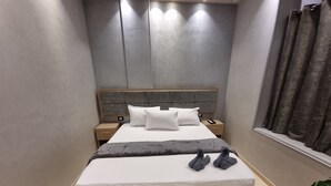 A modern hotel room with a large bed, a wooden headboard, a bedside table, and a nightstand. - Cairo Plaza Manchester Hotel (Cairo)