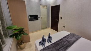 A modern hotel room with a bed, a flat-screen TV mounted on the wall, a potted plant, and a sliding door. - Cairo Plaza Manchester Hotel (Cairo)