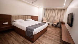 A modern hotel room with a large bed, a desk, a chair, and a TV. - Ricch Hotels (Hyderabad)