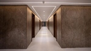 A long, narrow hallway with a marble floor and walls, leading to a distant point. - Ricch Hotels (Hyderabad)