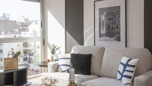 A modern living room with a sofa, a coffee table, and a large window overlooking a cityscape. - La Pergola 5F - Double Studio Interior (Castellón)