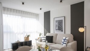 A modern living room with a sofa, dining table, and a large window with sheer curtains. - La Pergola 5F - Double Studio Interior (Castellón)