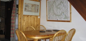 Un espace repas avec une table en bois et quatre chaises, une carte accrochée au mur et un panneau indiquant « Coin repas ».