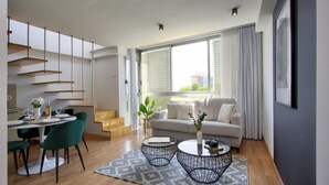 A modern apartment with a dining area, a living room with a sofa and coffee table, and a kitchen with a staircase.