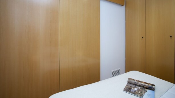 A bedroom with wooden wardrobes, a white mattress, and a magazine on the bed. - La Pergola 6G - Exterior Penthouse with Terrace (Castellón)
