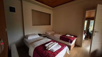 Een hotelkamer met twee bedden, een houten plafond en een raam met zonwering.