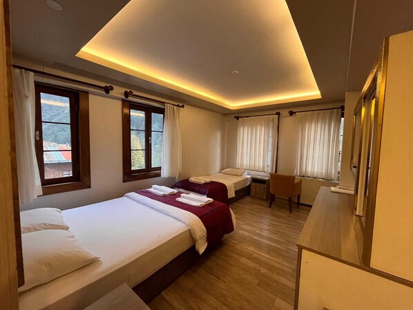 Een hotelkamer met twee bedden, een bureau en uitzicht.