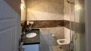 A bathroom with a wooden ceiling, a sink with a marble countertop, a toilet, and a glass shower enclosure. - Ayder Hotel  (Çamlıhemşin)