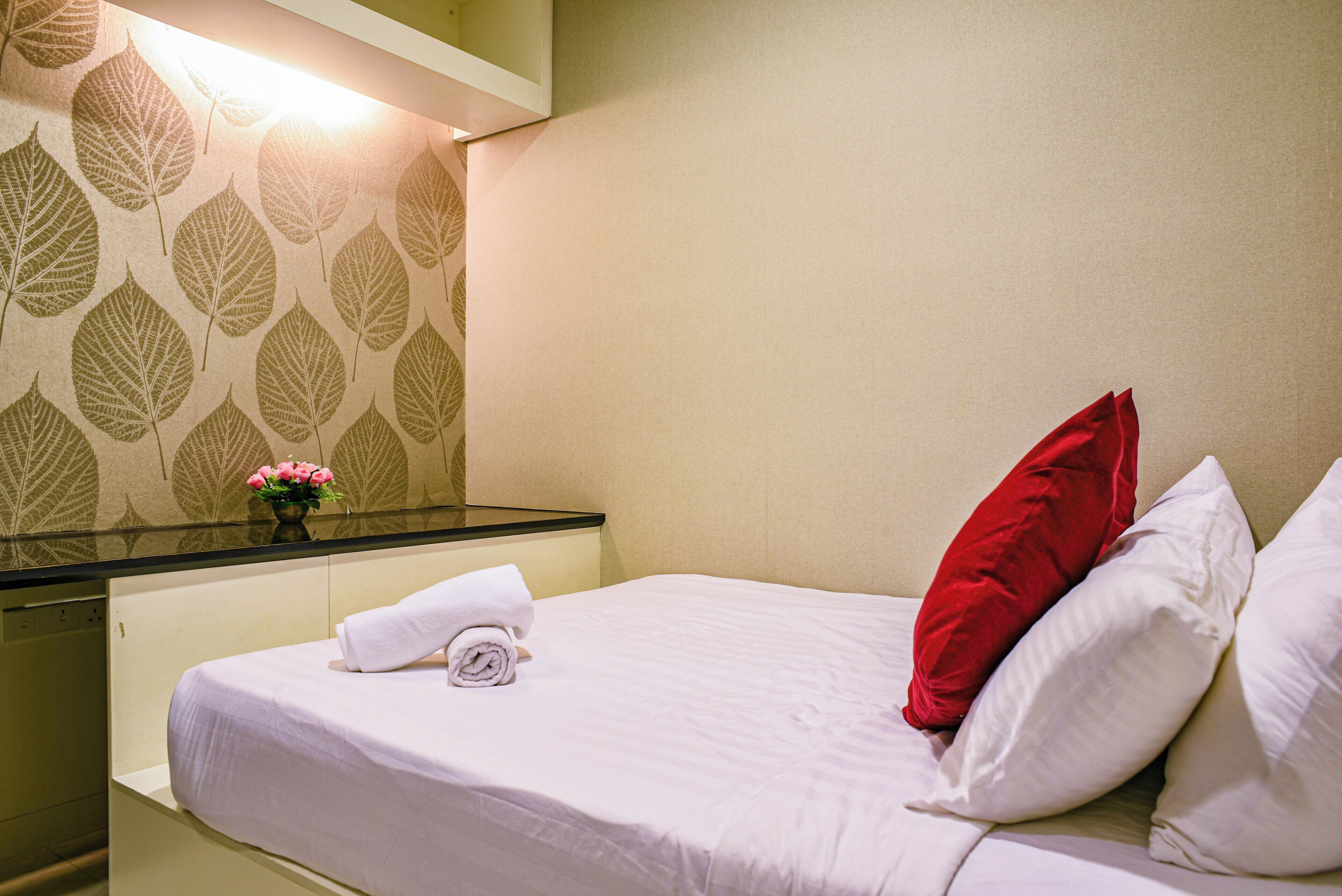 A hotel room with a bed, a nightstand, and a mirror.