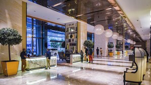 A modern lobby with a marble floor, a reception desk, and a seating area with a bench. - The Platinum KLCC By Aura Suites (Kuala Lumpur)